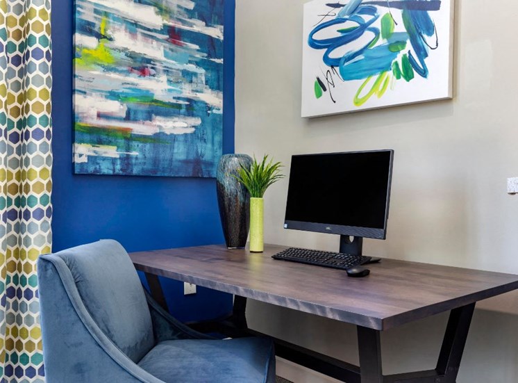 Computer Desk with Padded Chair Next to Blue Accent Wall
